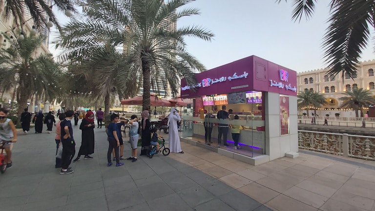 Outdoor scene of people enjoying ice cream in a sunny plaza.