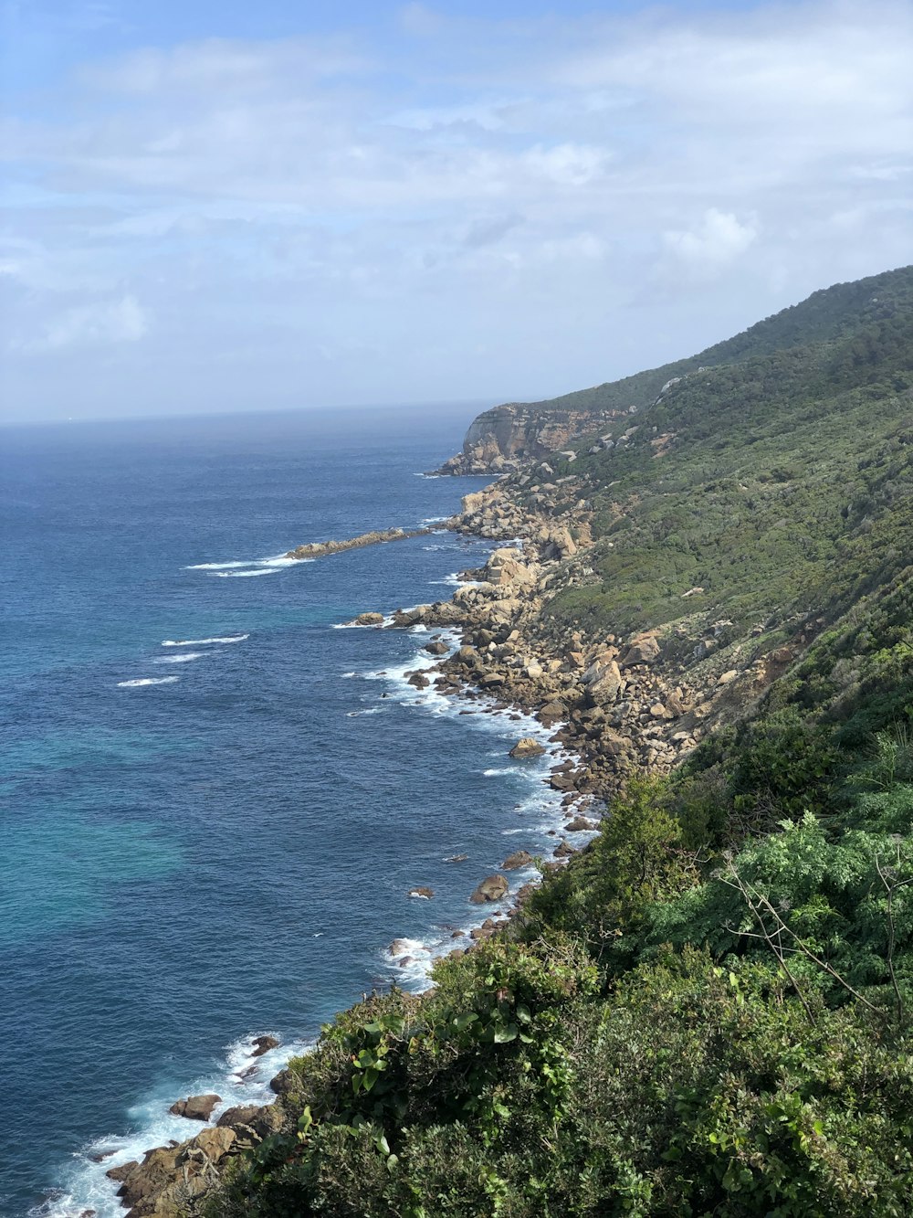 green and brown mountain beside body of water during daytime