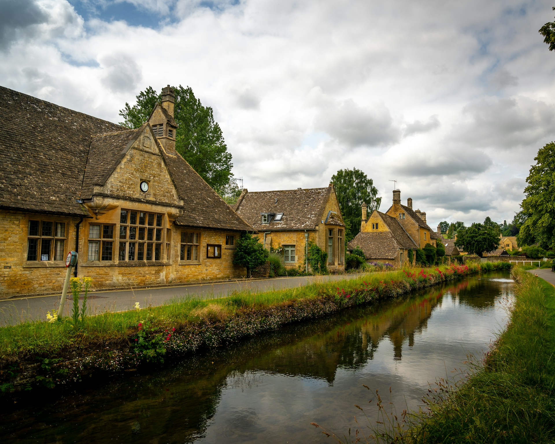 brown and gray house beside river under cloudy sky during daytime