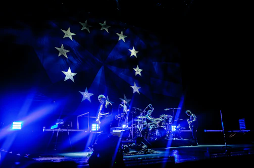 A vibrant shot of the band performing under glowing stage lights with electric blue accents.