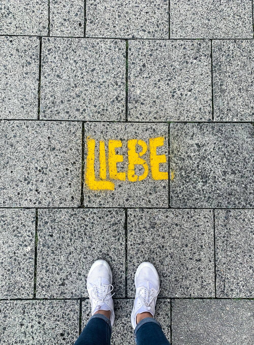 a person standing in front of a sidewalk with the word liebe painted on it