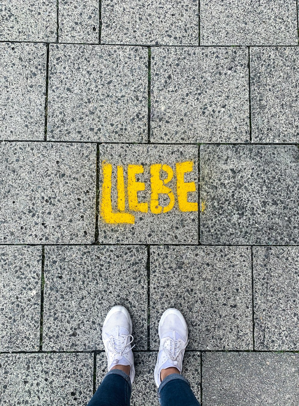 Una persona parada frente a una acera con la palabra Liebe pintada en ella