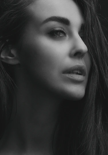 Elegant portrait of a serene woman surrounded by soft natural light and delicate textures.