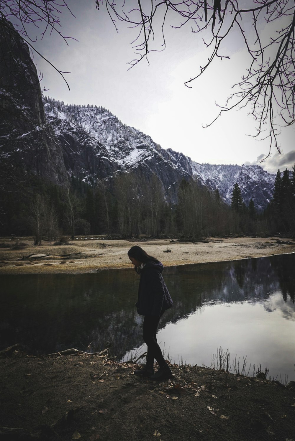woman in black jacket standing near lake during daytime