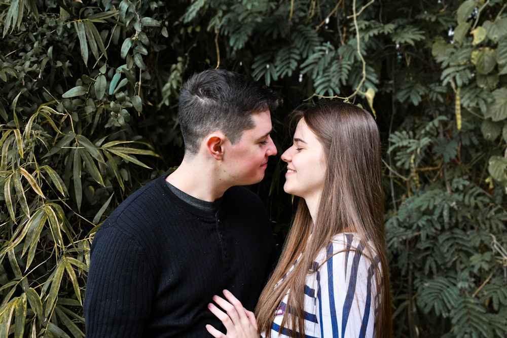 man in black sweater kissing woman in white and blue stripe shirt