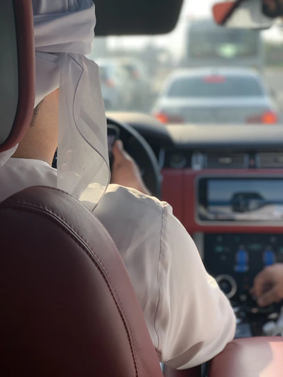 A friendly driver helping a passenger into a comfortable car ready for a trip from Saudi Arabia to Bahrain.