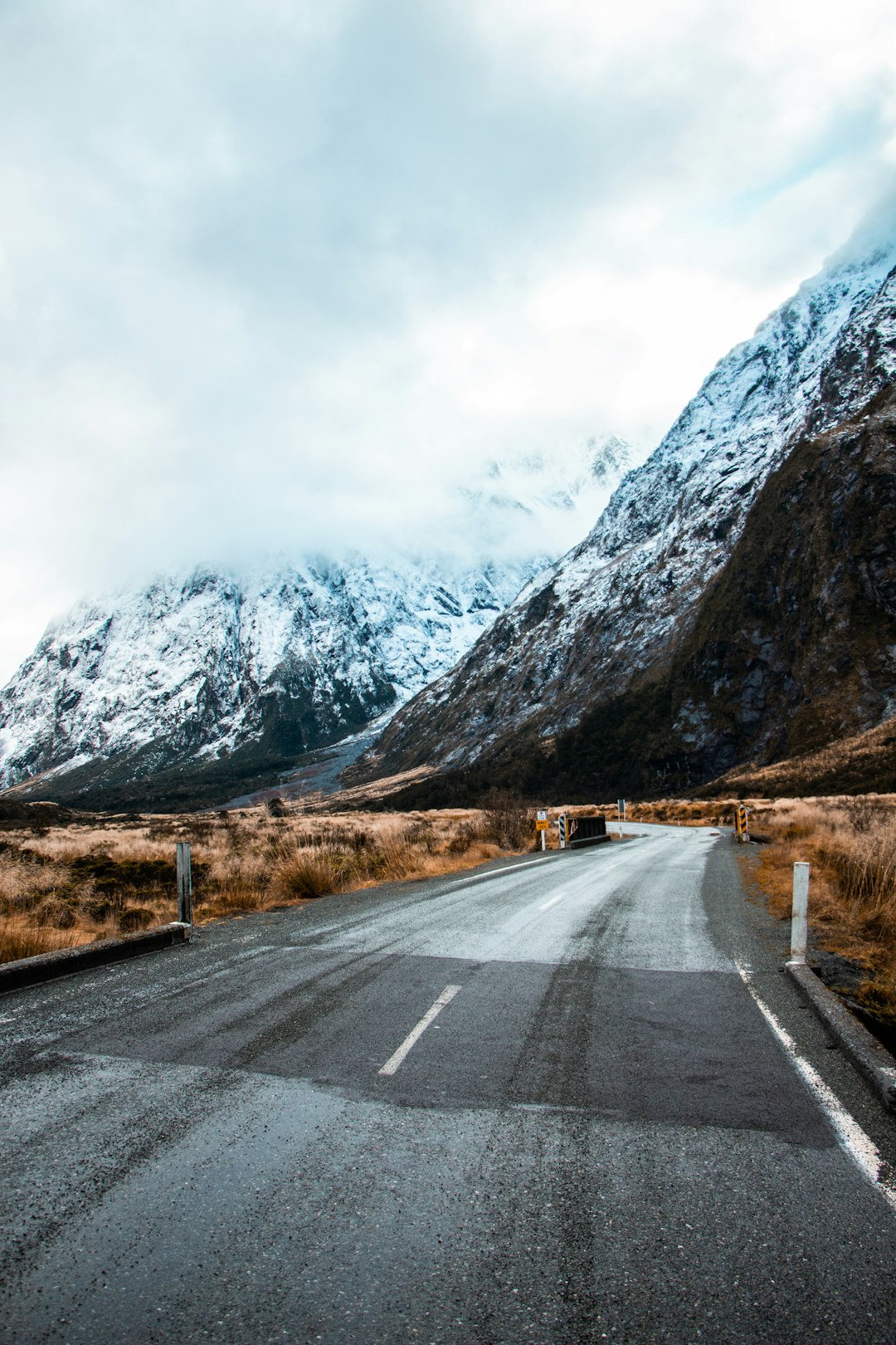 gray concrete road near mountain under white sky during daytime