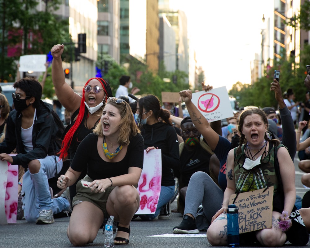 people sitting on gray concrete pavement during daytime