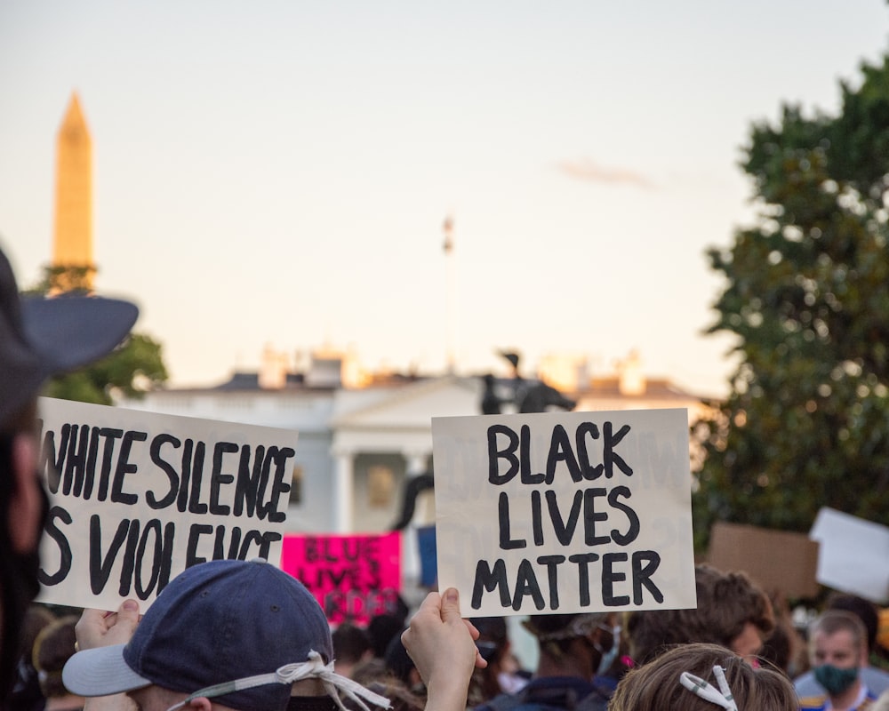 people holding a white and black signage during daytime