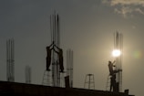 Workers installing steel panels on a large commercial structure at sunset.