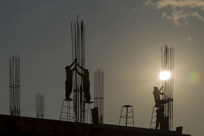 Construction site with workers reinforcing a structure at sunset.