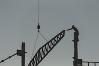 silhouette of man standing on top of tower crane