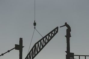 silhouette of man standing on top of tower crane