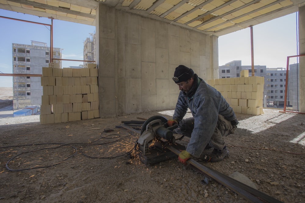 man in black jacket and black pants holding black and orange power tool