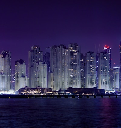 city skyline across body of water during night time