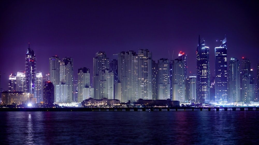 city skyline across body of water during night time