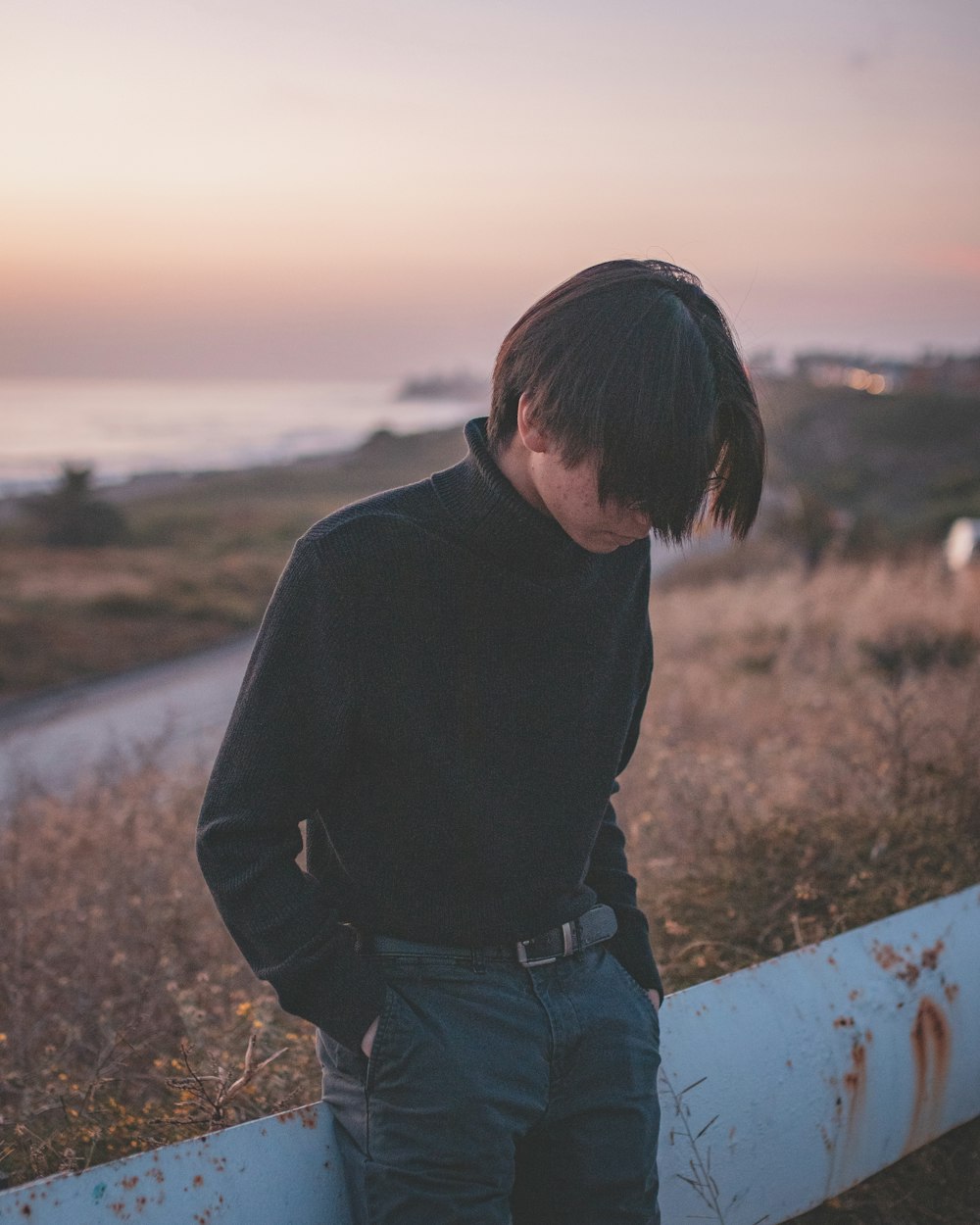 man in black sweater and blue denim jeans standing on brown field during daytime