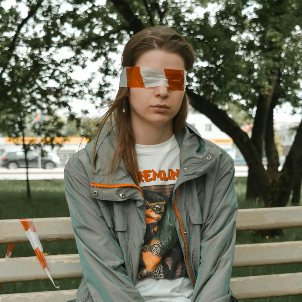 woman in gray hoodie sitting on brown wooden bench during daytime