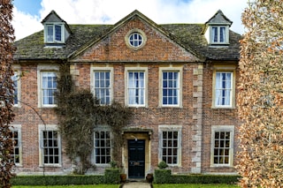 brown brick building with green grass lawn and trees