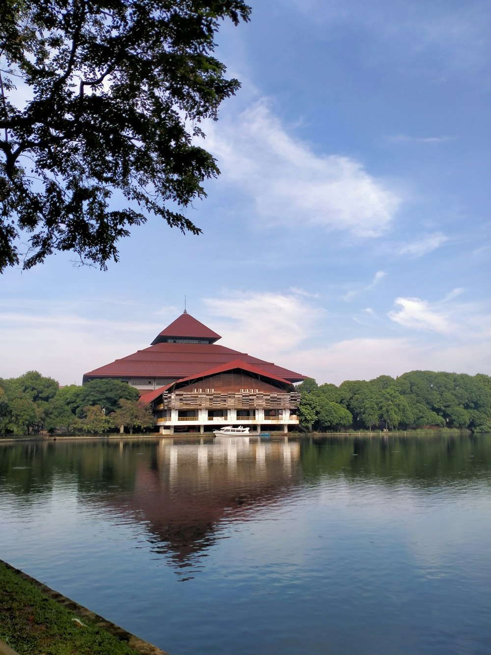 brown wooden house on lake near green trees under blue sky during daytime