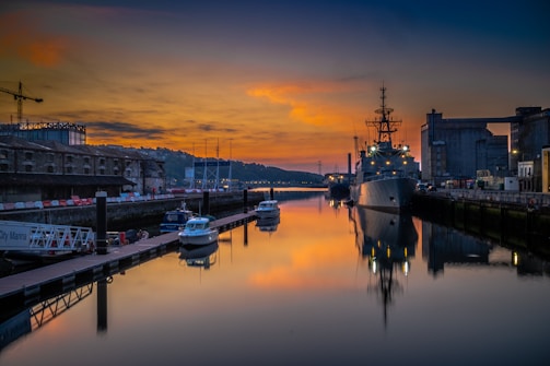 A calm harbor at sunset with cargo ships docked, symbolizing reliable marine logistics.