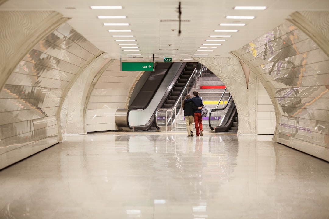 man in black t-shirt and blue denim jeans walking on white hallway