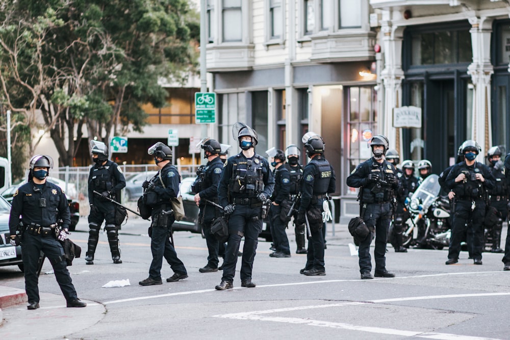 hommes en uniforme de camouflage noir et gris tenant un fusil pendant la journée