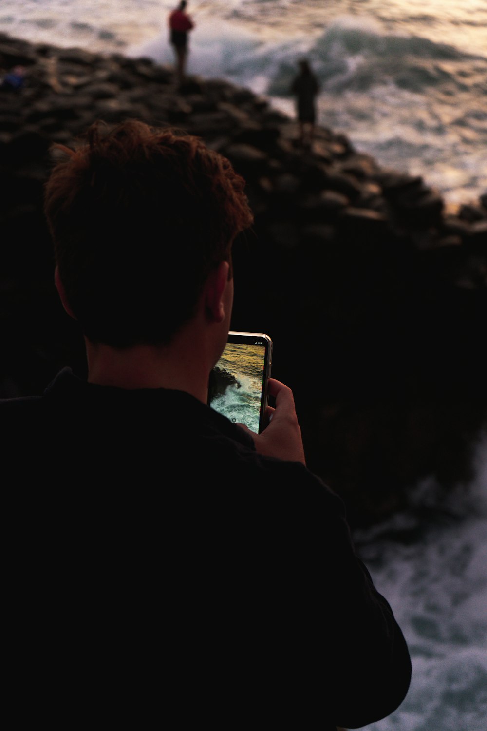 man in black shirt holding white smartphone