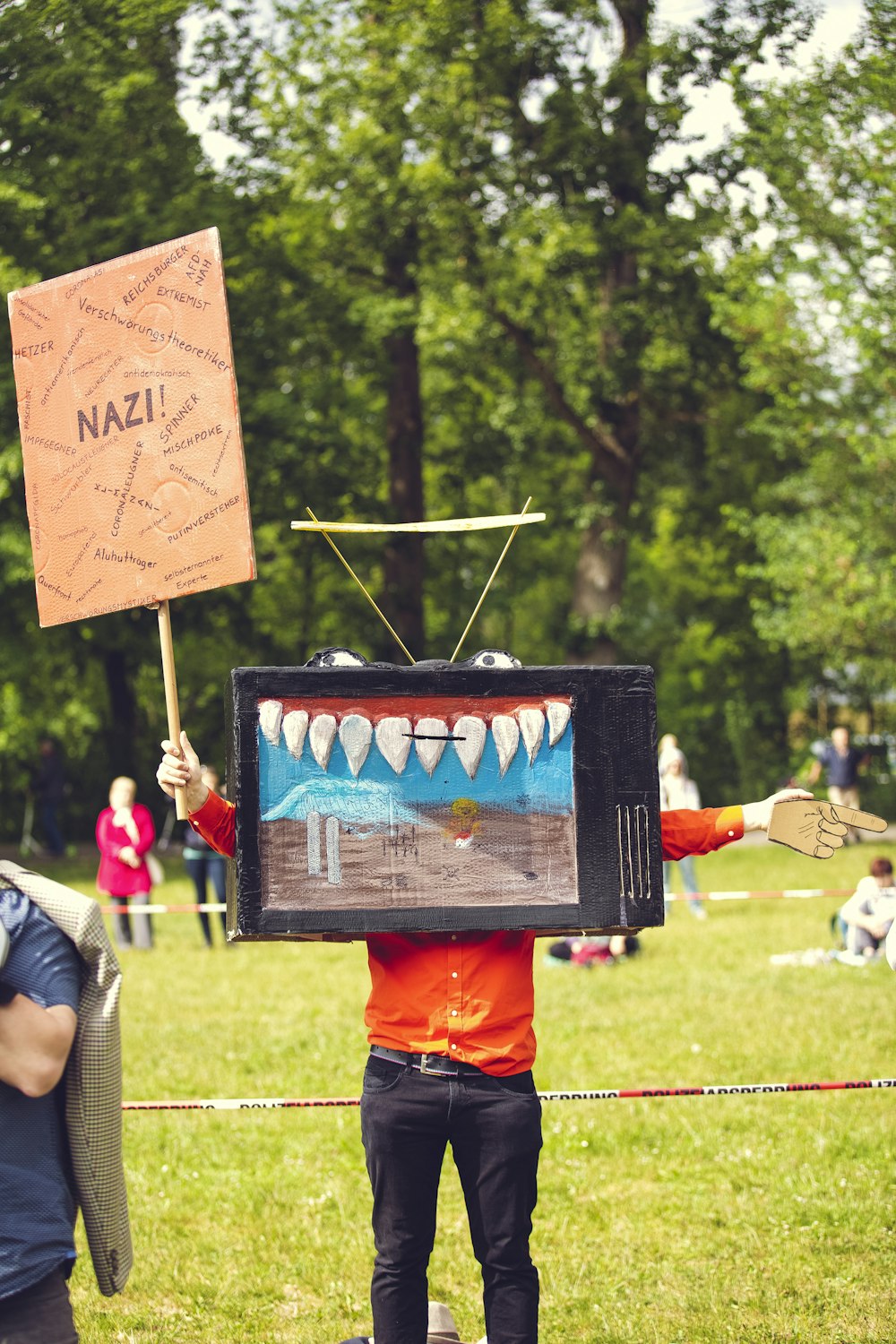 man in orange shirt holding black and red banner