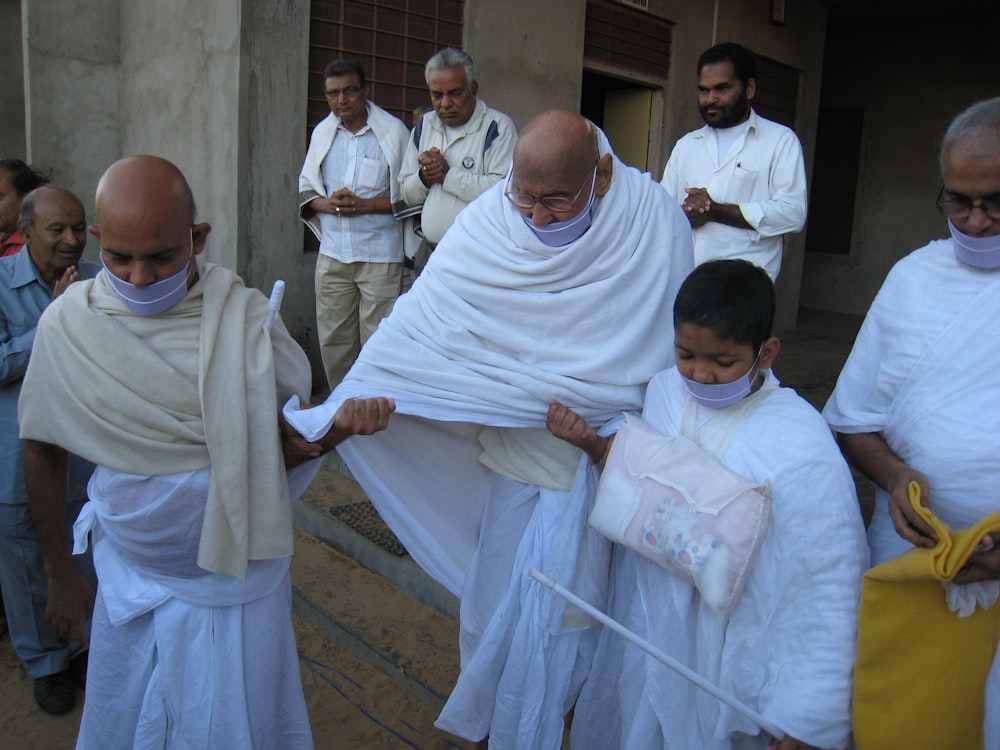 man in white thobe sitting on brown floor