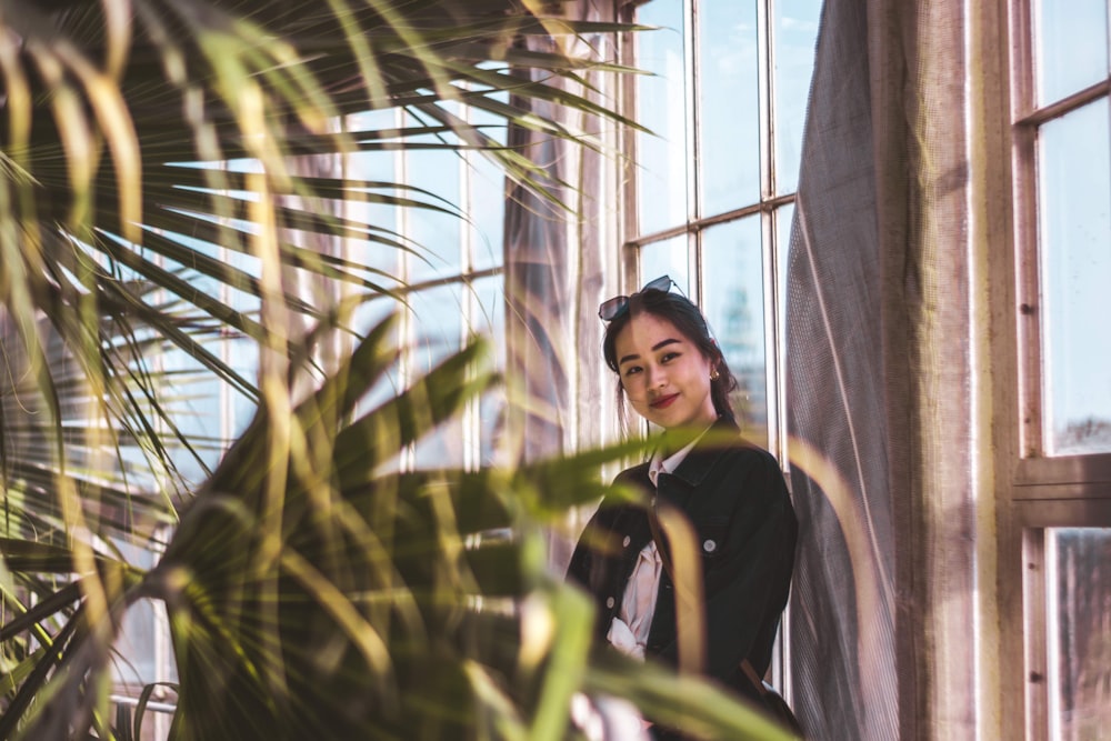 woman in black long sleeve shirt standing beside green plant