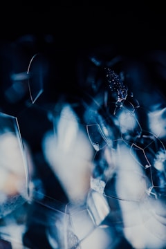 An abstract composition of overlapping translucent shapes against a dark background. These shapes exhibit a glass-like quality and interact with light, creating reflections and refractions that give a sense of depth and complexity. The interplay of light results in a dynamic and visually intriguing pattern.