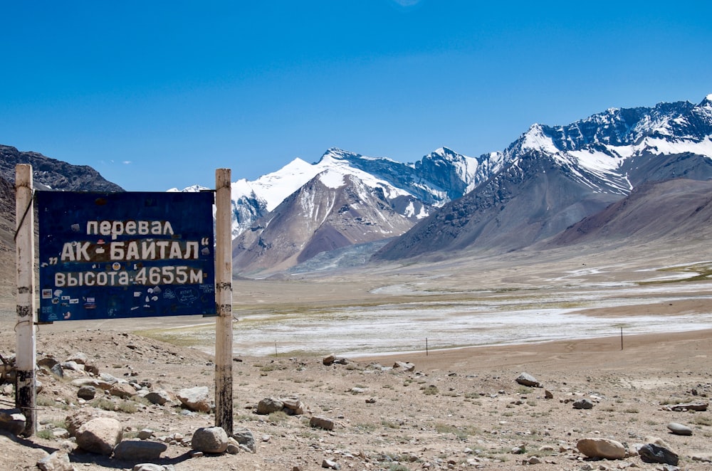 brown wooden signage near brown field and mountain during daytime