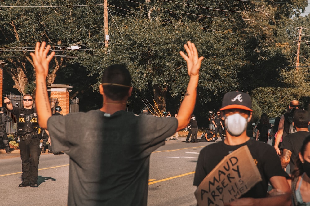 man in black crew neck t-shirt raising his right hand