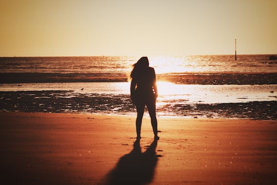 silhouette of woman walking on beach during sunset in Dunkerque France