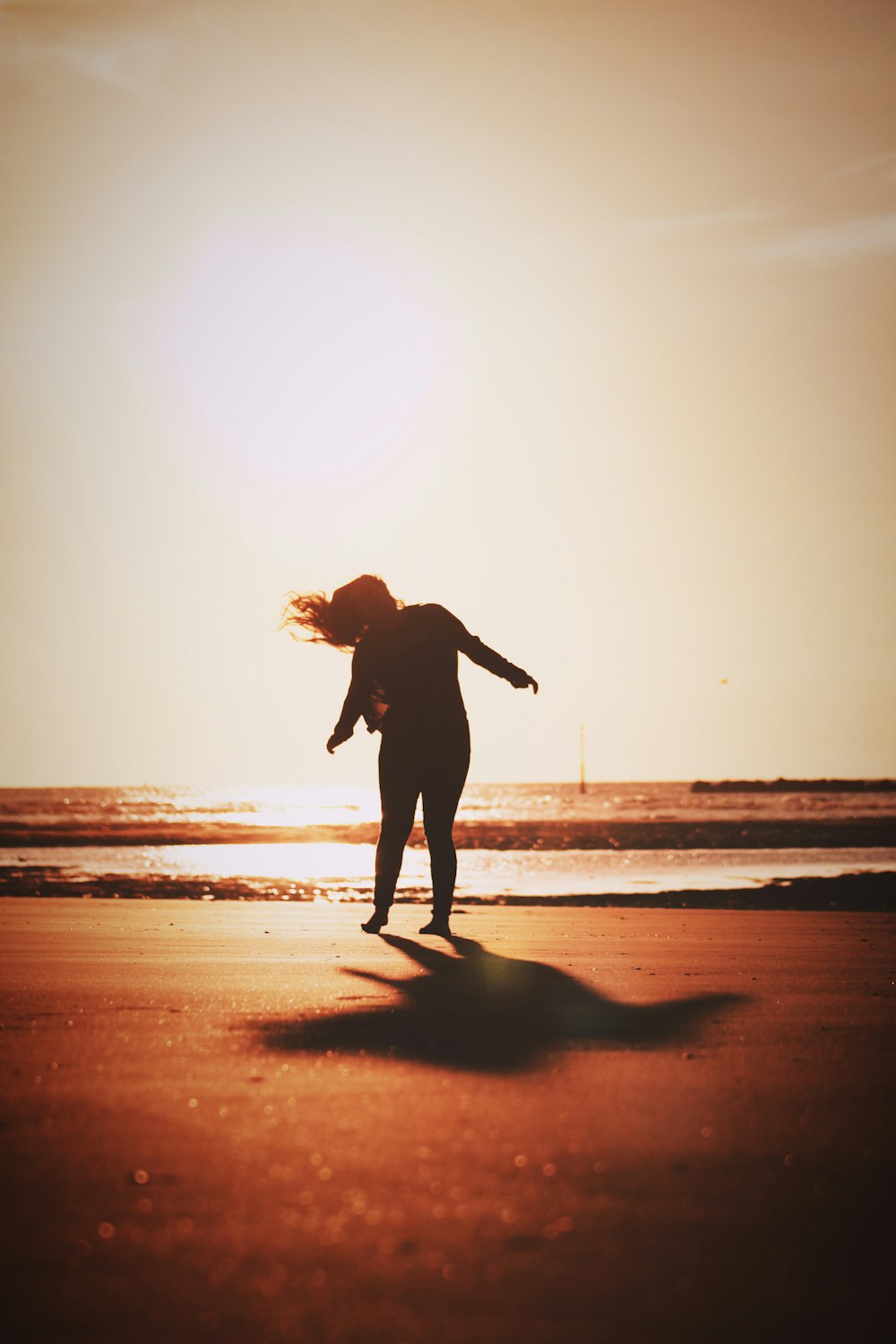 silhouette of woman walking on beach during sunset