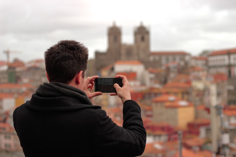 man in black jacket taking photo of brown concrete building during daytime