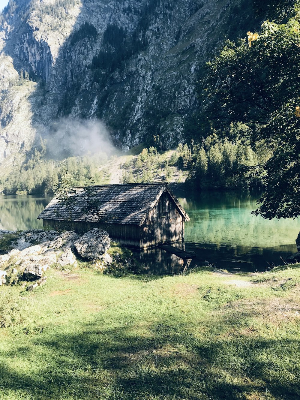 brown wooden house near lake and green trees during daytime