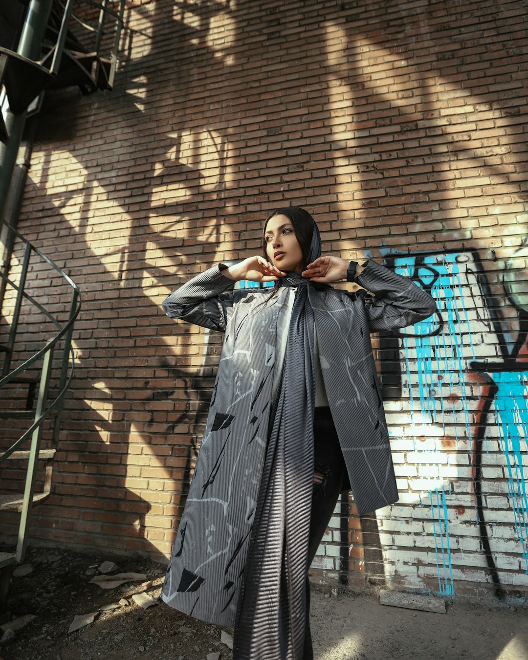 woman in black coat standing near brown brick wall