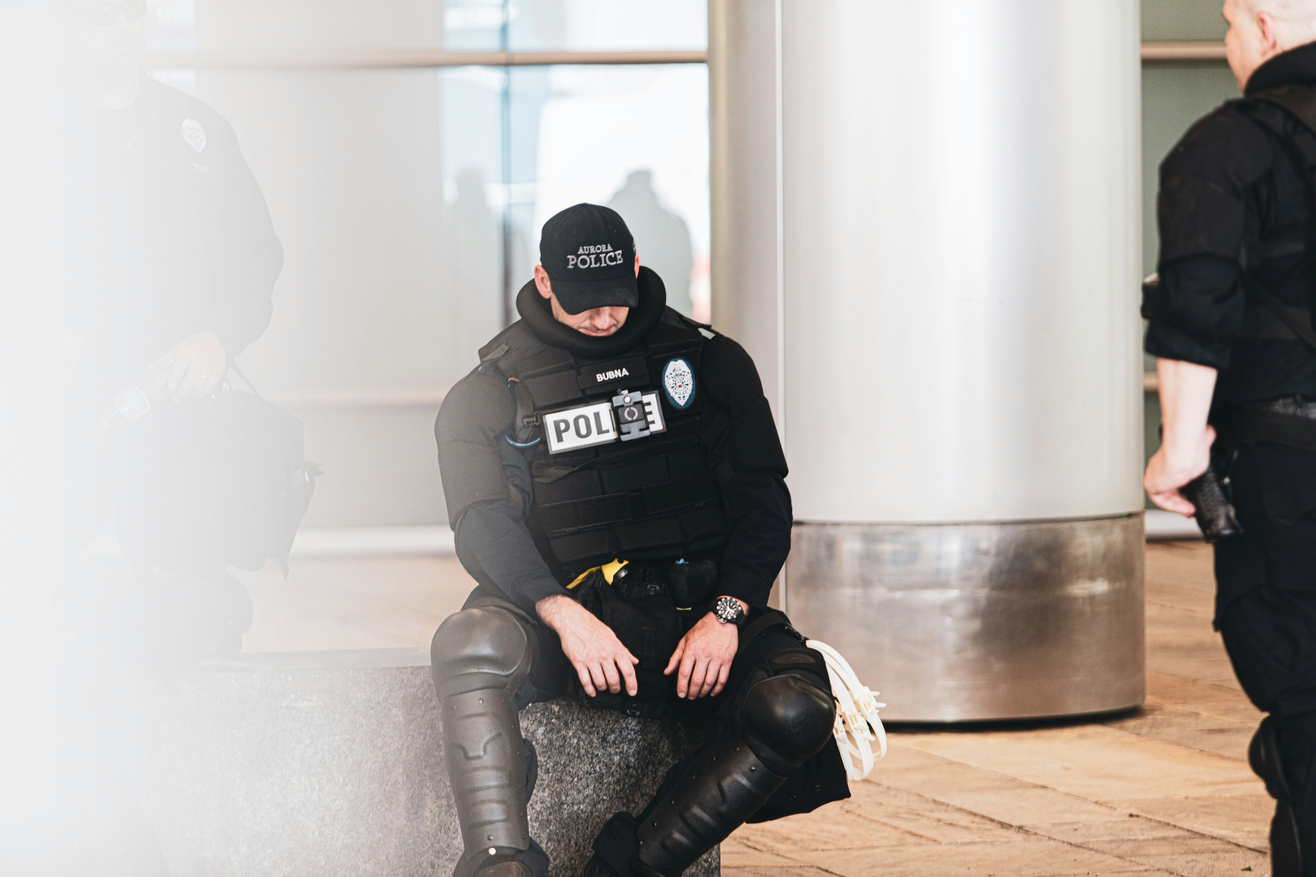 man in black and gray jacket and black pants sitting on brown wooden floor