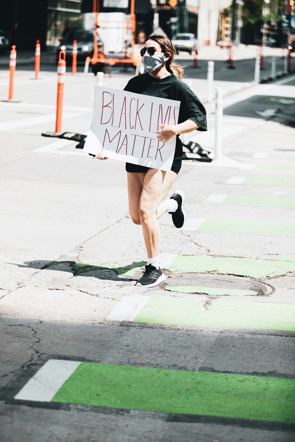 Femme en veste noire et short marron marchant sur le trottoir pendant la journée