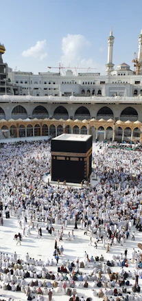 A large crowd of people in white clothing surrounding the Kaaba in Mecca.