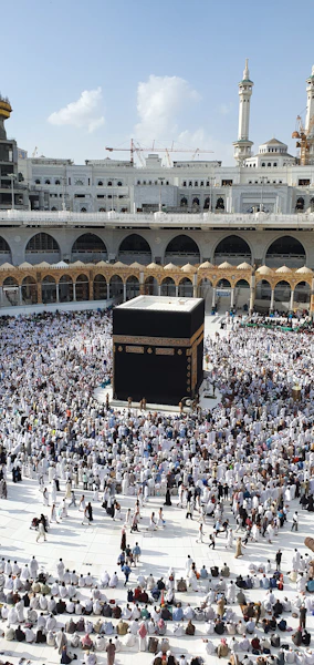 A large crowd of people in white clothing surrounding the Kaaba in Mecca.