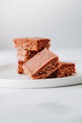 Close-up of a fudgy brownie with a glossy chocolate crust on a minimalist beige plate.