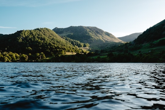 green mountains beside body of water during daytime in Ullswater United Kingdom