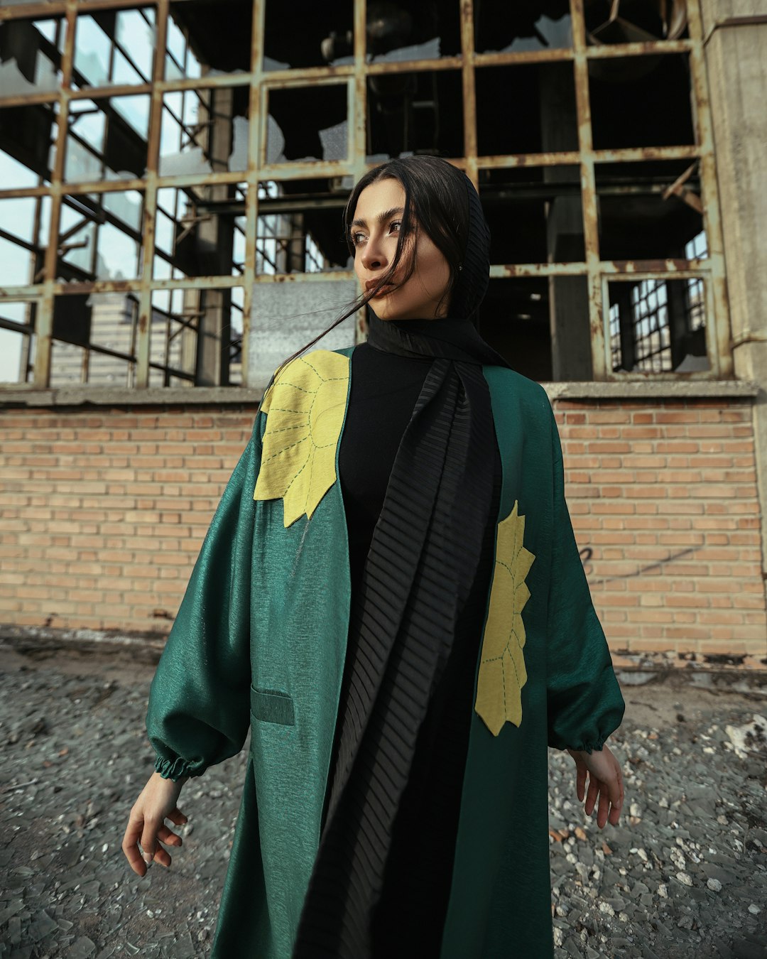 woman in green and black long sleeve dress standing near brown brick wall