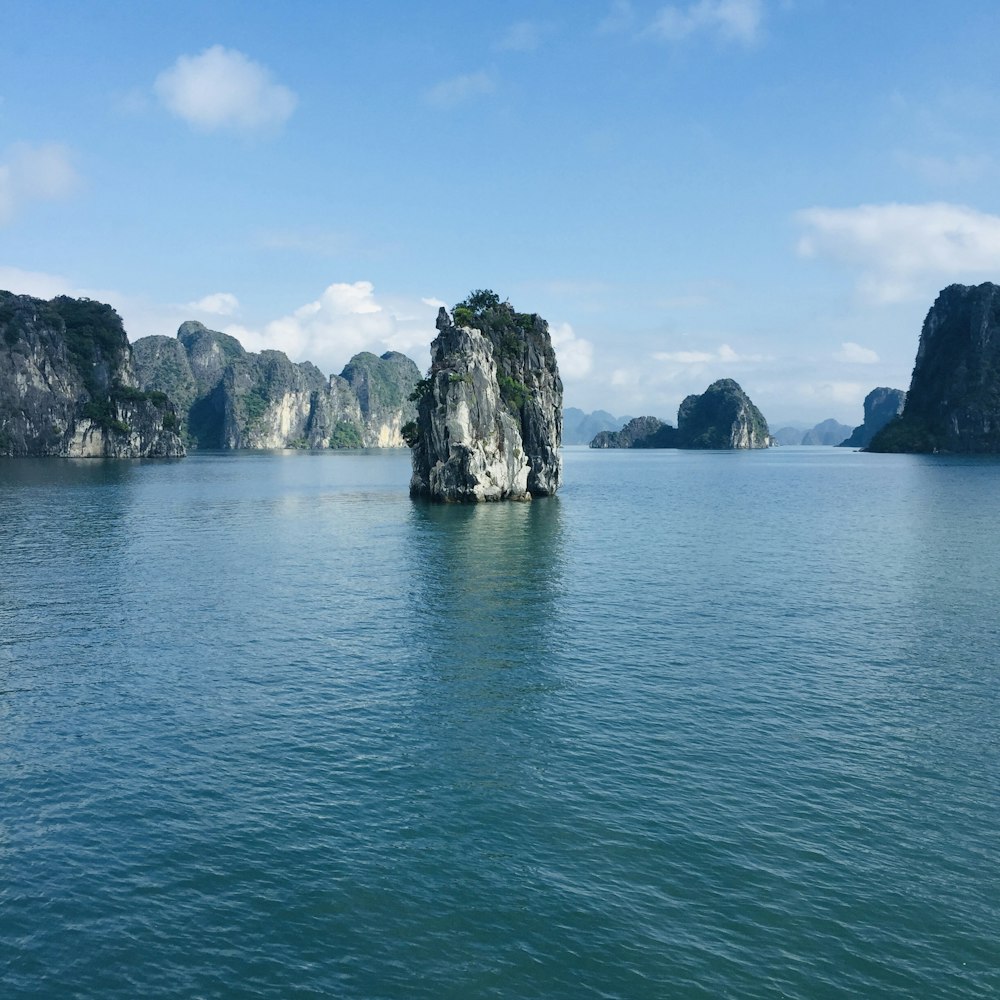 昼間の青空の下、灰色の岩層近くの青い海