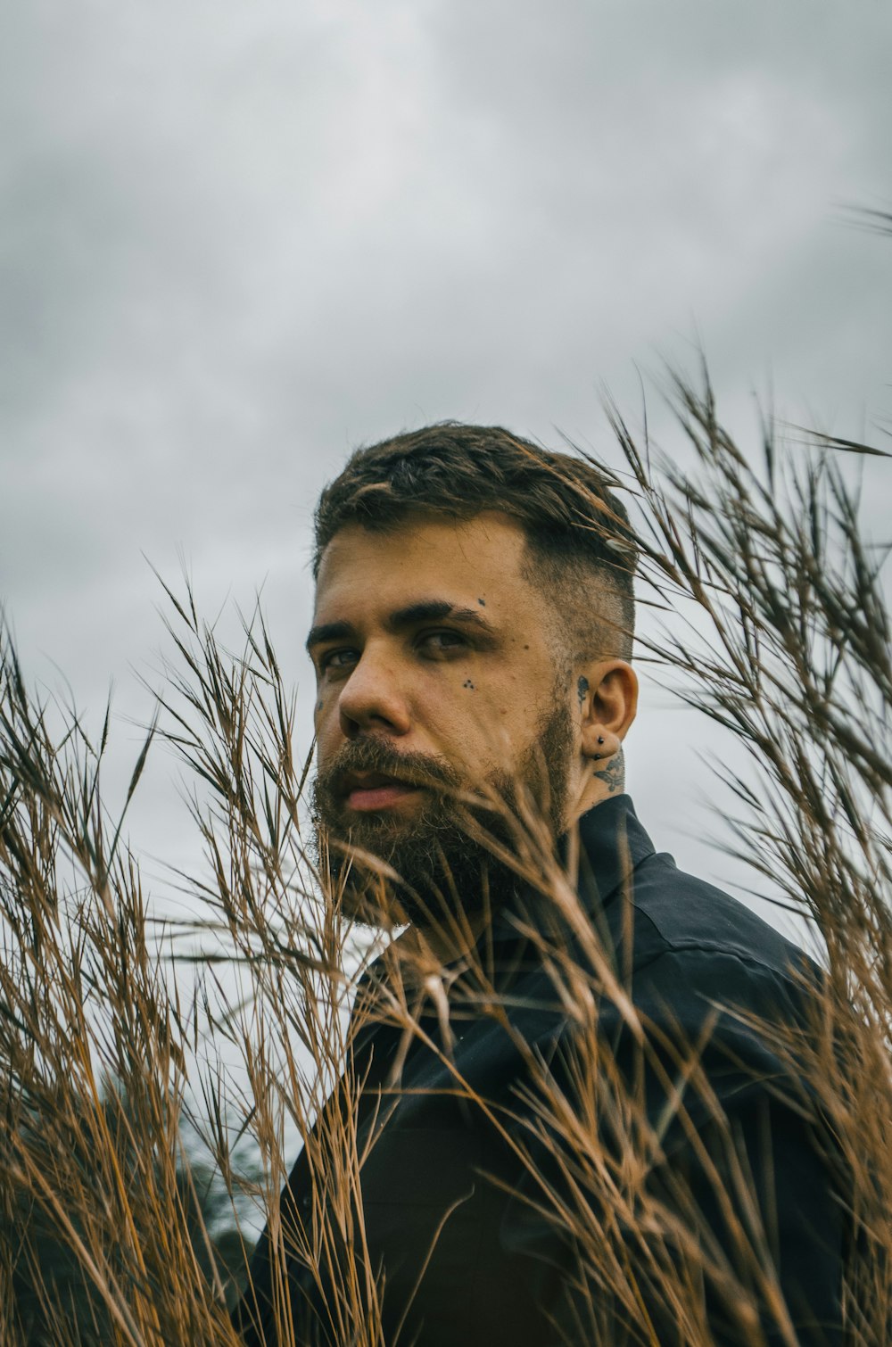 man in blue jacket standing near brown grass during daytime