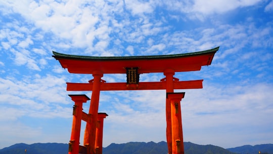 brown wooden cross on top of mountain under white clouds during daytime in Itsukushima Shrine Japan
