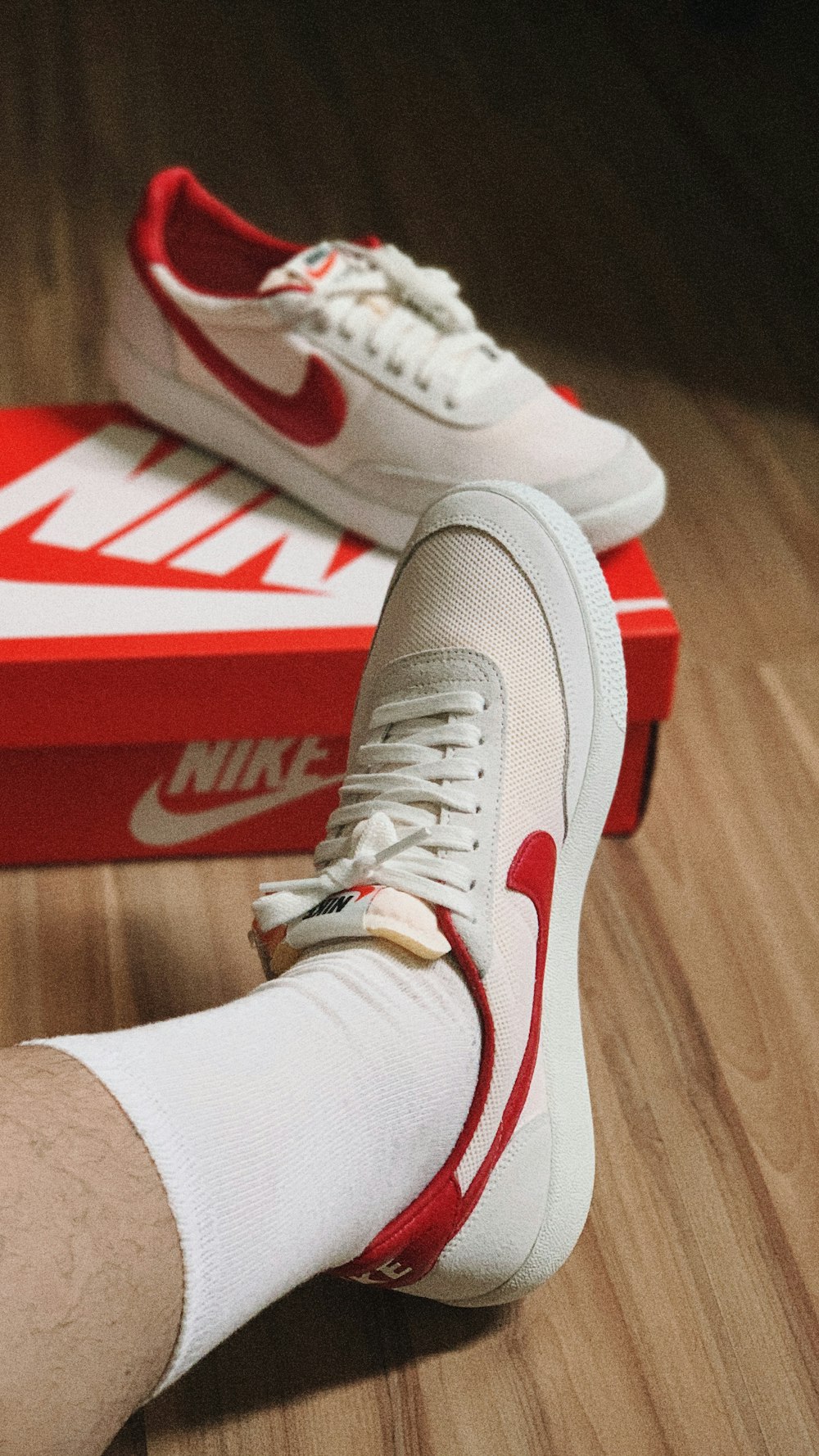 Personne portant des chaussures de sport Nike blanches et rouges